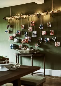 a dining room with green walls and pictures hanging on the wall, along with a wooden table