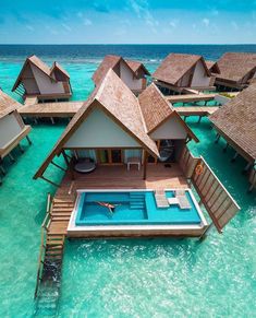 an aerial view of a resort over the water with some huts on stilfets