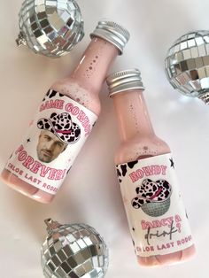 three bottles of pink liquid sitting on top of a white table next to disco balls