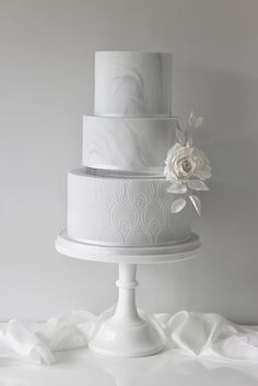 three tiered white wedding cake with flowers on top