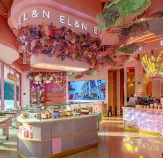 the inside of a restaurant with flowers hanging from the ceiling and colorful decorations on the walls