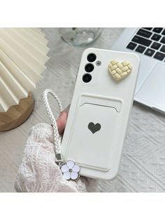 a person holding a white phone case with a heart on the back and two hearts attached to it