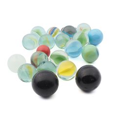 several different colored glass marbles on a white surface with one black and one yellow