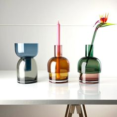 three different colored vases sitting on top of a white table next to each other