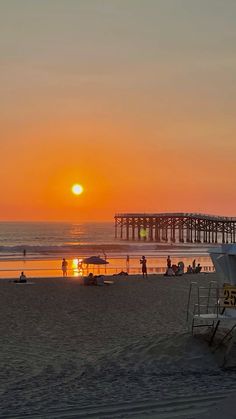 the sun is setting at the beach with people on it