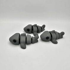 three gray fish shaped objects on a white surface