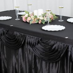 a black table cloth with flowers and candles on it is set up for a formal function