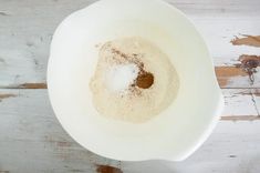 a white bowl filled with powdered sugar on top of a wooden table