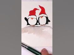 someone is drawing two penguins on a piece of paper