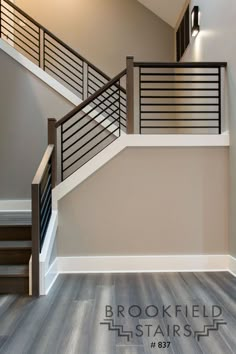 an empty room with stairs and wood flooring