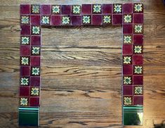 a red and green mosaic tile frame sitting on top of a wooden floor