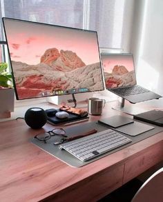 two computer monitors sitting on top of a wooden desk next to a keyboard and mouse