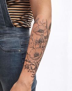 a woman's arm with flowers on it and a striped shirt in the background