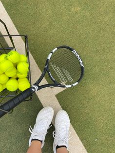 a person standing next to a racket with tennis balls in it