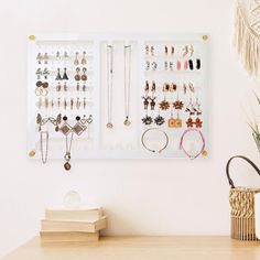 a wall mounted jewelry rack on a white wall next to a vase with flowers in it