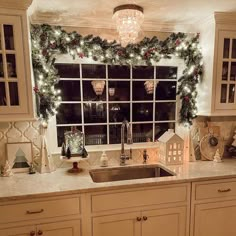 a kitchen decorated for christmas with wreaths and garland on the window sill above the sink