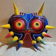 a blue mask with yellow spikes on it's face and two horns sticking out