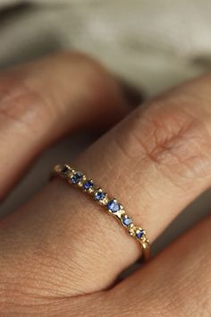 a woman's hand with a yellow gold band and blue sapphire stones on it