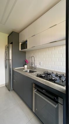 a modern kitchen with stainless steel appliances and white tile backsplash, along with gray cabinets