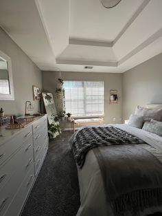 a bedroom with a bed, dressers and window in it's center area