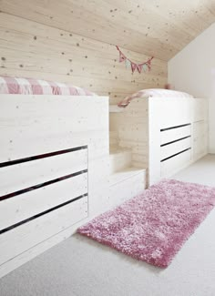 a bedroom with two white bunk beds and pink rugs