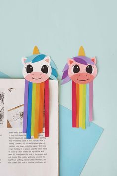 two unicorns made out of colored paper on top of a book with an open page