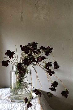 a vase filled with flowers sitting on top of a white tablecloth covered table next to a window