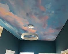 a bedroom with blue walls and clouds painted on the ceiling