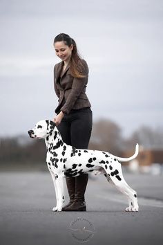 a woman standing next to a dalmatian dog