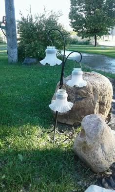 two lamps are sitting on some rocks in the grass