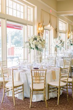 the tables are set with white flowers in vases and centerpieces on them