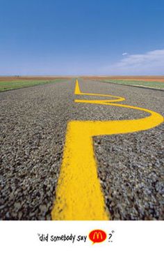 an empty road with a yellow arrow painted on the side and blue sky in the background