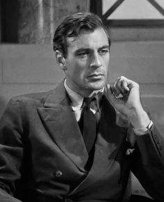 black and white photograph of a man in suit sitting down with his hand on his chin