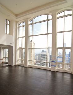 an empty room with large windows and hardwood floors