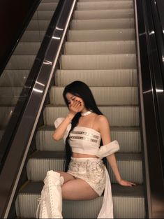 a woman sitting on an escalator talking on her cell phone while wearing high heels