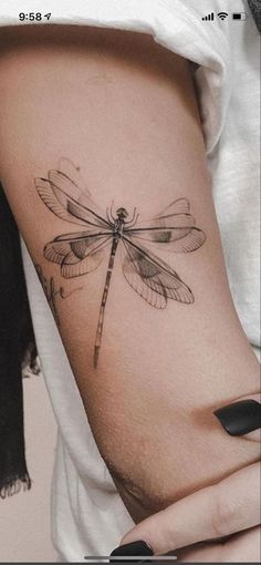 a woman's thigh with a dragonfly tattoo on it