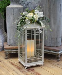 a white candle in a metal cage with flowers