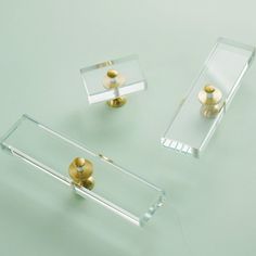 two glass shelves with gold knobs on them and one is holding a pair of handles