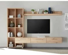 a flat screen tv sitting on top of a wooden shelf next to a bookcase