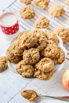 a white bowl filled with oatmeal cookies next to an apple