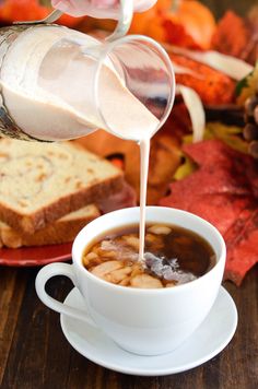 someone pours milk into a cup of soup on a plate with bread and autumn leaves