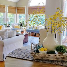 a living room filled with lots of furniture and yellow flowers in a vase on top of a table