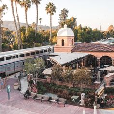 a train traveling past a building next to palm trees