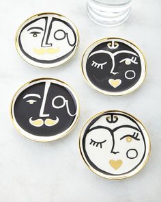 three black and white plates with faces painted on them next to a glass vase filled with water