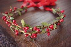 a close up of a wreath on a table with red flowers and leaves around it