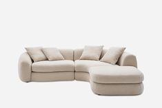 a large sectional couch with pillows on it's back and arms, sitting in front of a white background