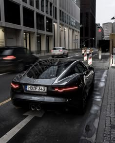 a black sports car is parked on the side of the road in front of some tall buildings