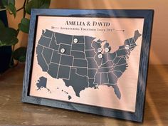 a wooden framed map of the united states with pins in each state and names on it