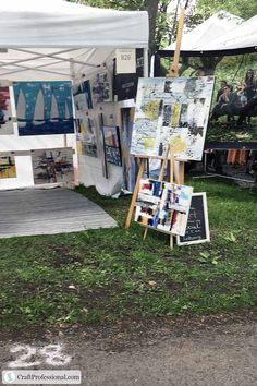 an easel is sitting in the grass next to a sign with pictures on it