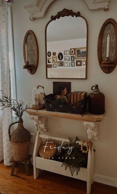 there is a mirror on the wall above a shelf with baskets and plants in it